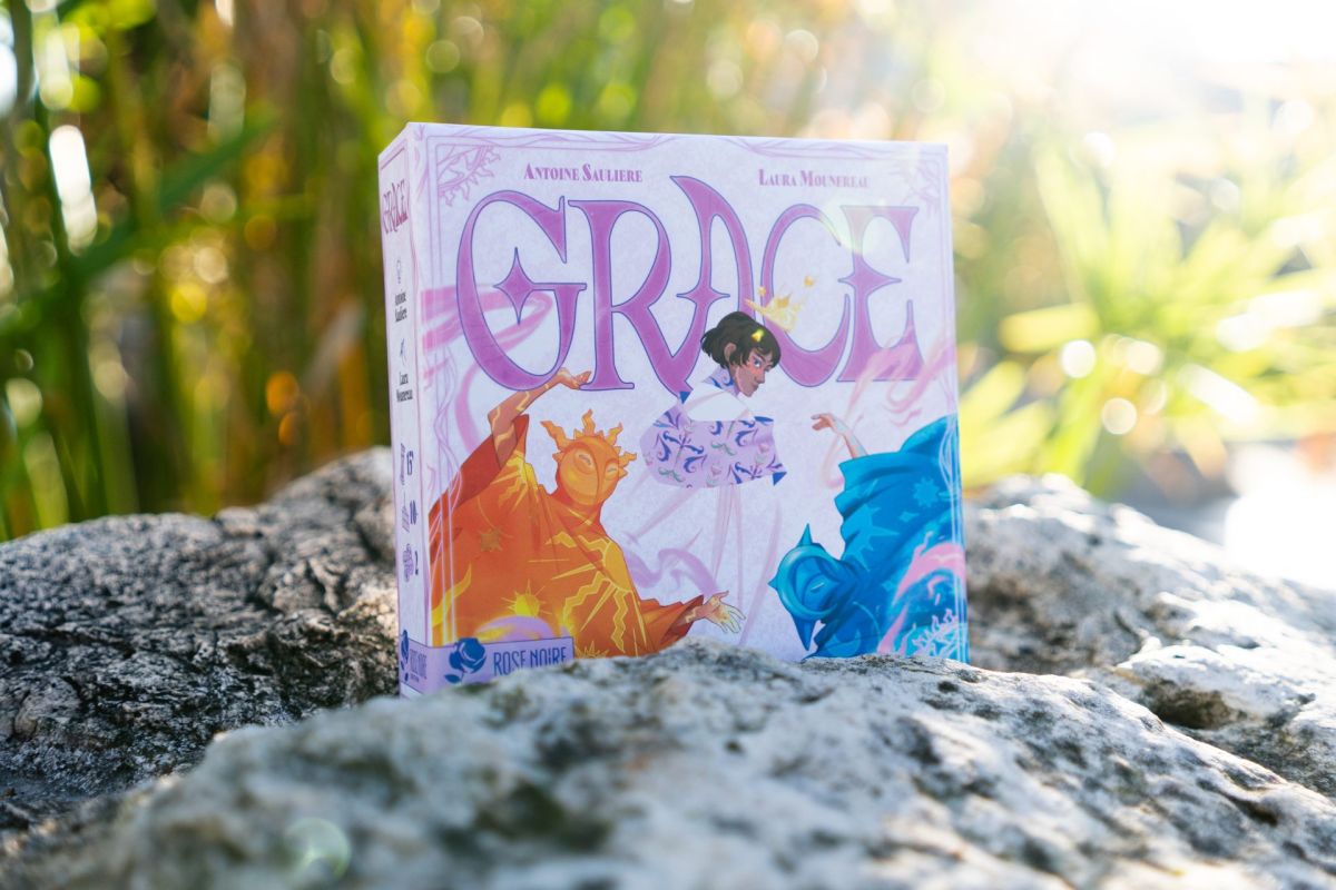 La boîte du jeu Grace posée sur une pierre, à contre-jour dans la végétation.